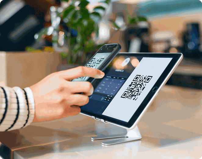 Smartphone scannant le QR code affiché sur une tablette posée sur un comptoir